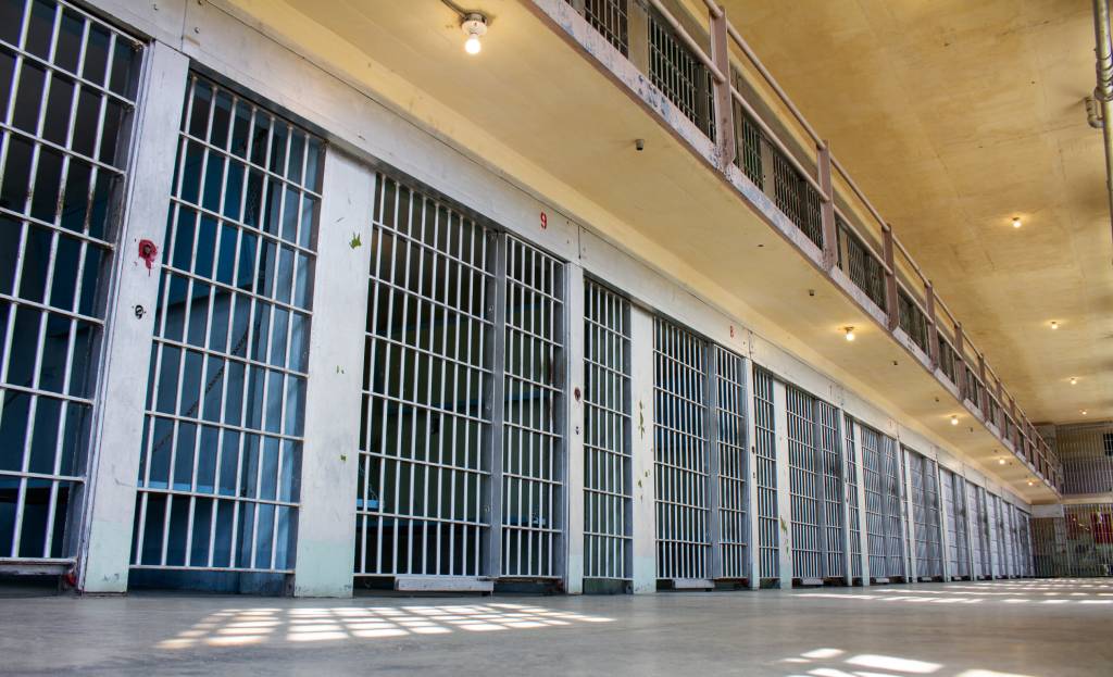 A prison cell block with many cells and bars.